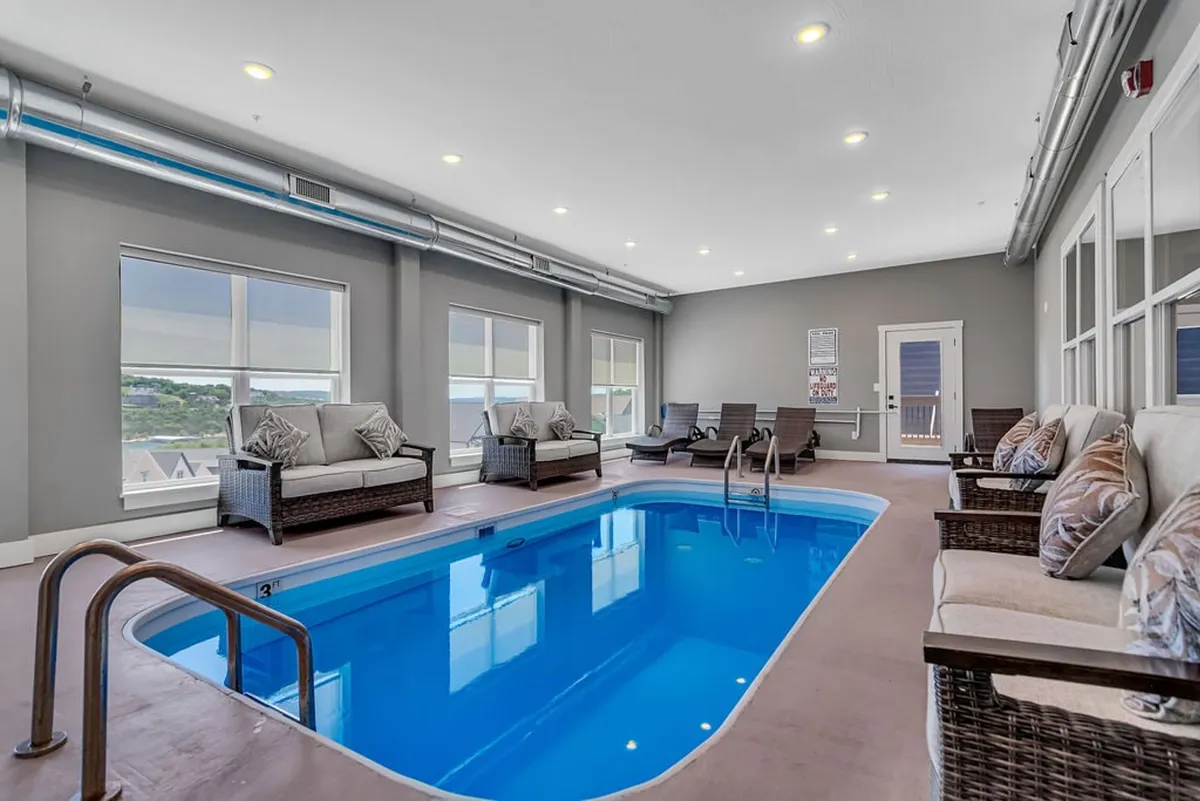 This image displays an inviting indoor pool with comfortable seating and expansive windows that let in natural light. The tranquil scene highlights the luxury of a private pool for swimming, lounging, and socializing, creating an atmosphere perfect for year-round aquatic fun.