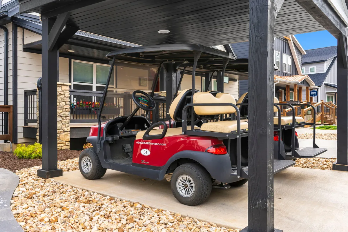 An exterior shot featuring a Club Car golf cart parked beside a covered area with stylish neighborhood architecture in the background. The scene suggests both ease of movement and access to nearby amenities, while maintaining a relaxed, upscale mood.